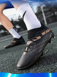 Close-up detail of professional black flyknit soccer cleats with long spikes on grass.