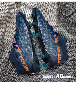 Close-up of navy blue flying knit soccer cleats featuring orange NKADA logo and AG studs