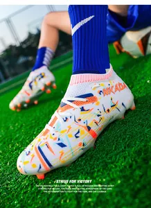 Detail shot of white fly-knit soccer cleats with colorful pattern on green turf