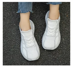 Dettaglio dall'alto di sneakers a calzino in maglia bianca traspirante indossate su asfalto
