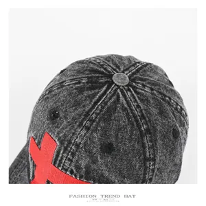 Detailansicht einer verwaschenen schwarzen Jeans-Baseballkappe mit rotem Kreuz-Stickerei