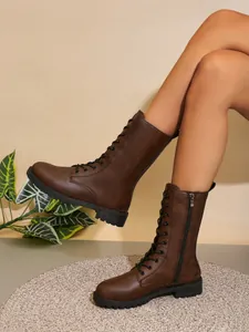 Botas de combate marrones a media pierna con cremallera en las piernas de la modelo