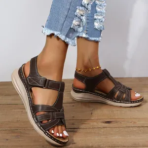 Close-up detail view of brown Roman style wedge sandals featuring cross straps and soft sole