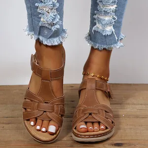 Brown retro Roman wedge sandals with decorative cross-strap stitching shown on model