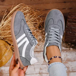 Close-up detail view of grey retro casual sneakers with white stripes and gum sole