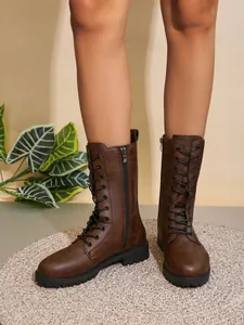 Vista detallada de botas de media pantorrilla marrones vintage con cremallera y cordones
