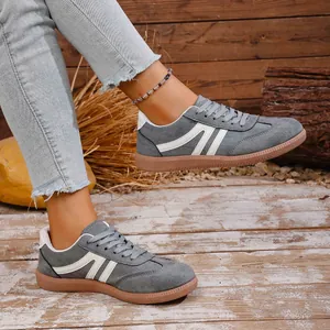 Detailed side view of retro grey casual sneakers with white stripes and gum sole