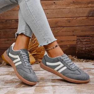 Detailed view of grey retro sneakers with white stripes and brown rubber soles