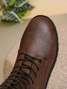 Detalle en primer plano del acabado en cuero marrón de una bota militar retro con cordones
