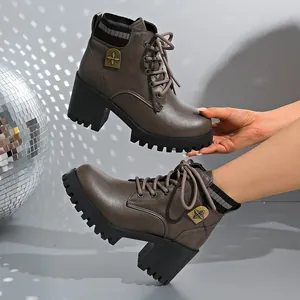 Side detail of brownish-grey lace-up Martin boots with chunky heel and cross emblem.