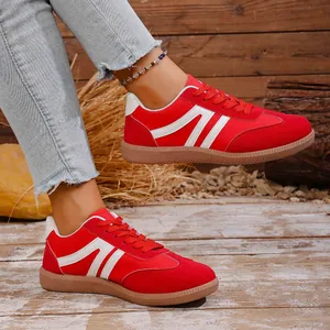 Detail view of retro red casual sneakers with white stripes and gum soles worn with jeans