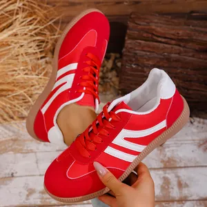 Close-up of red and white retro casual sneakers with suede texture on a rustic wooden background.