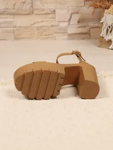 Detail view of the anti-slip treaded platform sole and chunky heel of a tan sandal