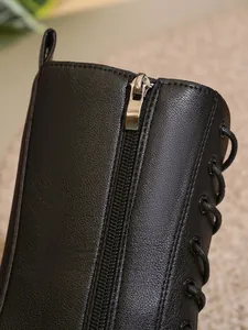 Primer plano de una bota de cuero negro con cremallera lateral metálica y cordones