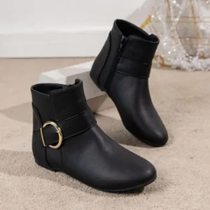 Detail view of black leather ankle boots with gold buckle and side zipper.