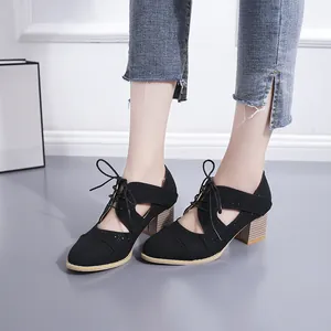 Détail des chaussures vintage noires à lacets avec motifs ajourés et talons blocs épais