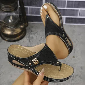 Detailed view of stylish black wedge thong sandals with metal buckle and stitching
