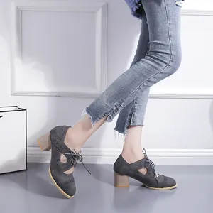 Détail de chaussures grises vintage à talons épais avec lacets et découpes ajourées