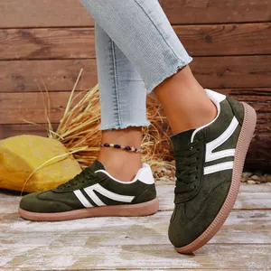 Close-up of olive green retro suede sneakers with white stripes and flat brown sole