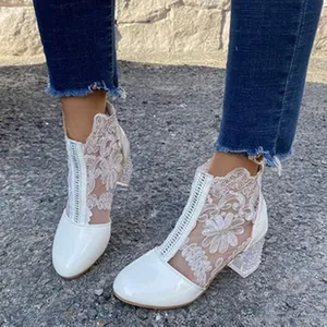 Close-up of white floral lace ankle boots with pearl-embellished block heel