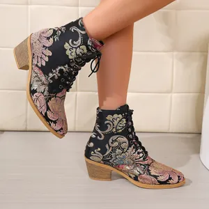 Close-up of vintage floral embroidered ankle boots with chunky heel and lace-up detail.