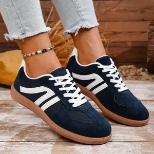 Close-up of women's navy blue retro sneakers with white stripes and gum soles.