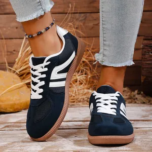 Close-up of navy blue retro sneakers with white stripes on rustic wooden background.