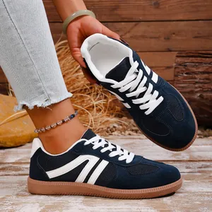 Close-up detail of navy blue retro sneakers featuring white stripes and a classic gum sole