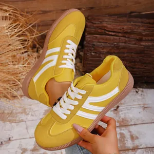Close-up detail of yellow retro casual sneakers with white stripes and round toe