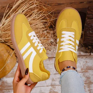 Detail of yellow retro suede sneakers for women featuring white stripes and gum soles
