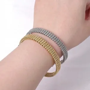 Detailopname van getextureerde geweven roestvrijstalen open armbanden in goud en zilver.