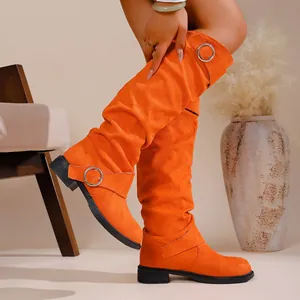 Close-up of vibrant orange suede over-the-knee slouch boots with metallic buckle