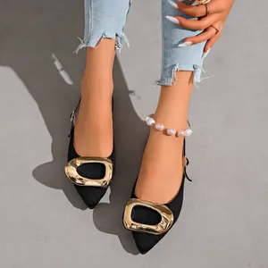 Close-up detail of French style black pointed-toe flats with an elegant oversized gold buckle
