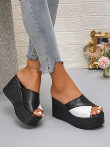 Detailweergave van zwart-witte wedge sandalen op model met comfortabele plateauzool