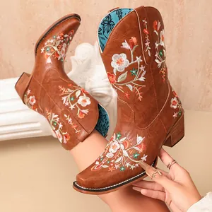 Macro view showing the intricate vintage floral embroidery on these brown leather cowboy boots