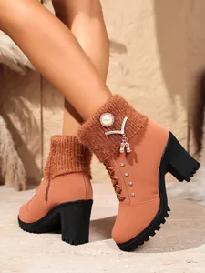 Detailansicht modischer orangefarbener Stiefeletten mit Strickbündchen und Perlen-Strass-Anhängern