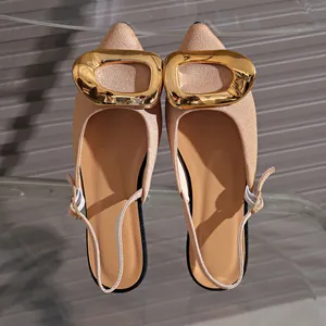 Macro detail view of elegant French style pointed-toe flat sandals with oversized gold buckle