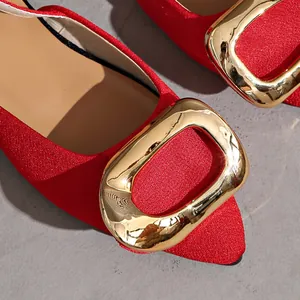 Macro detail of red pointed-toe flats with elegant oversized gold buckle decoration