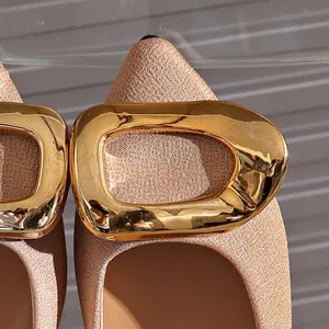 Close-up detail of champagne gold glitter flat sandals with a large metallic buckle