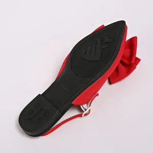 Macro detail of the non-slip black sole and sizing on a red pointed-toe bow flat sandal