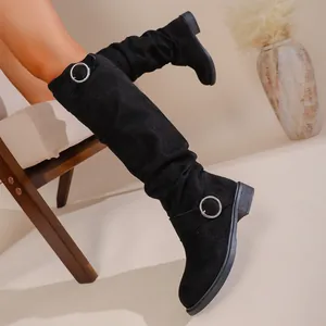 Detail view of black slouchy knee-high boots with silver buckle and chunky heel