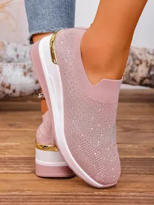 Close-up detail of pink fly-woven wedge shoes with sparkling rhinestone accents.