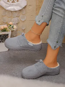 Close-up of grey fleece-lined slippers worn with jeans for a cozy winter look.