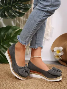 Κοντινό πλάνο γκρι loafers με πλατφόρμα και διακοσμητικό φιόγκο στα πόδια μοντέλου
