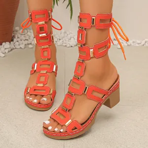 Close-up of vibrant orange lace-up gladiator sandals with gold metal buckle accents