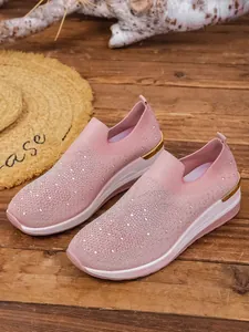 Detailed view of pink slip-on wedge shoes featuring shimmering rhinestone accents.