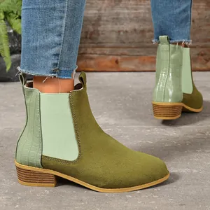 Close-up of olive green suede Chelsea boots with crocodile pattern and wooden heel