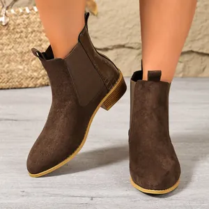 Close-up view of brown suede Chelsea boots with elegant crocodile texture details