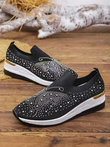 Black flying knit wedge sneakers with vibrant butterfly rhinestone pattern on wooden floor