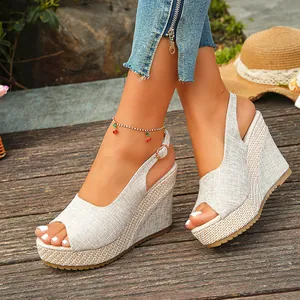 Detail view of linen peep-toe wedge sandals with woven platform on a boardwalk.